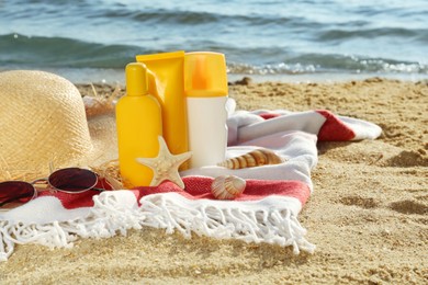 Sun protection products and beach accessories on blanket near sea, space for text