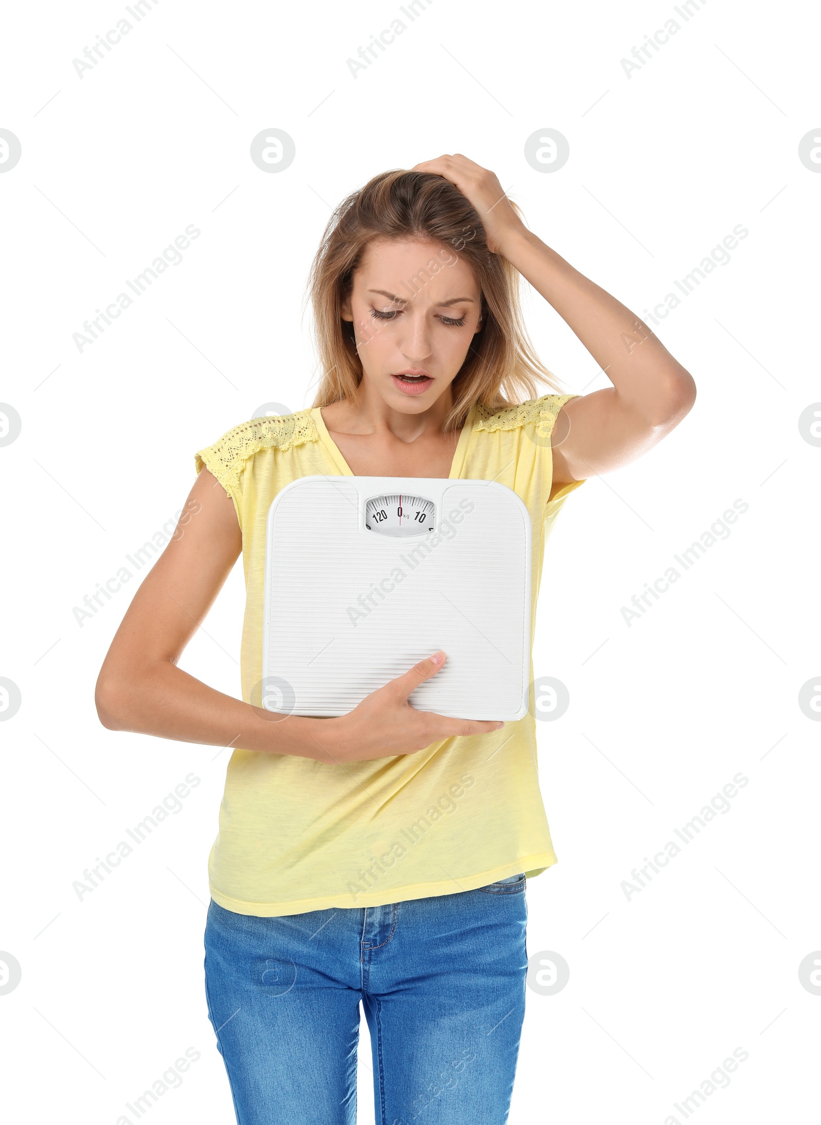 Photo of Worried young woman holding bathroom scales on white background. Weight loss diet