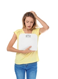 Worried young woman holding bathroom scales on white background. Weight loss diet