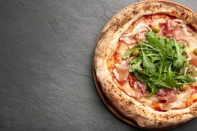 Tasty pizza with meat and arugula on black table, top view. Space for text