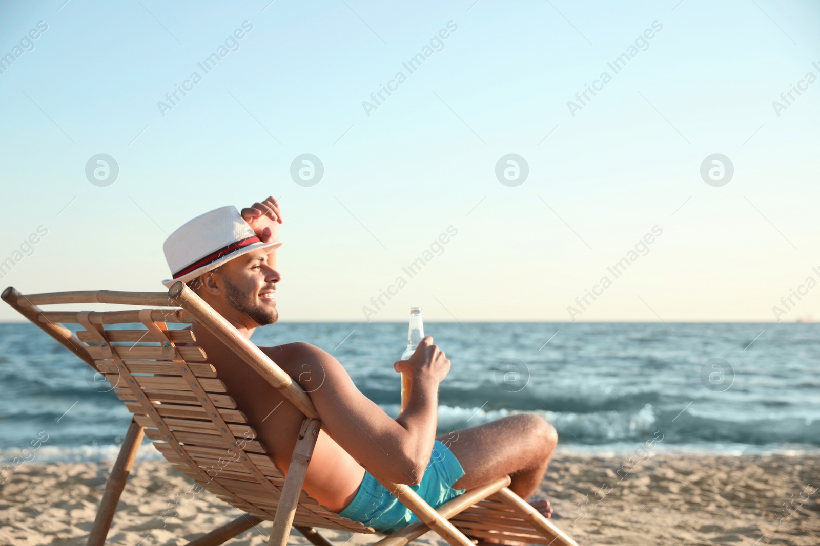 Photo of Young man relaxing in deck chair on beach near sea