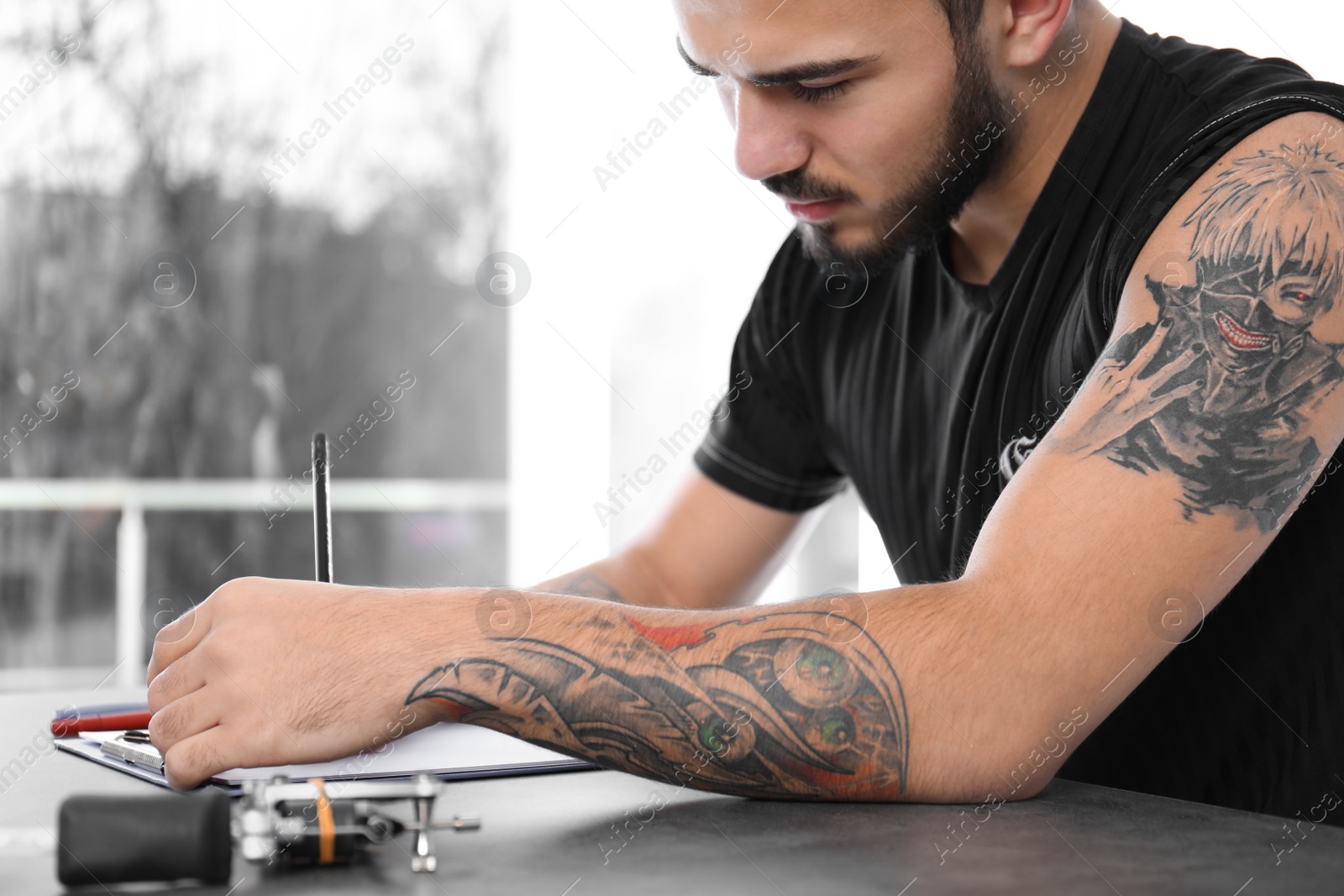 Photo of Professional tattoo artist drawing sketch at table indoors