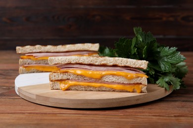 Photo of Delicious grilled sandwiches with ham, cheese and parsley on wooden table