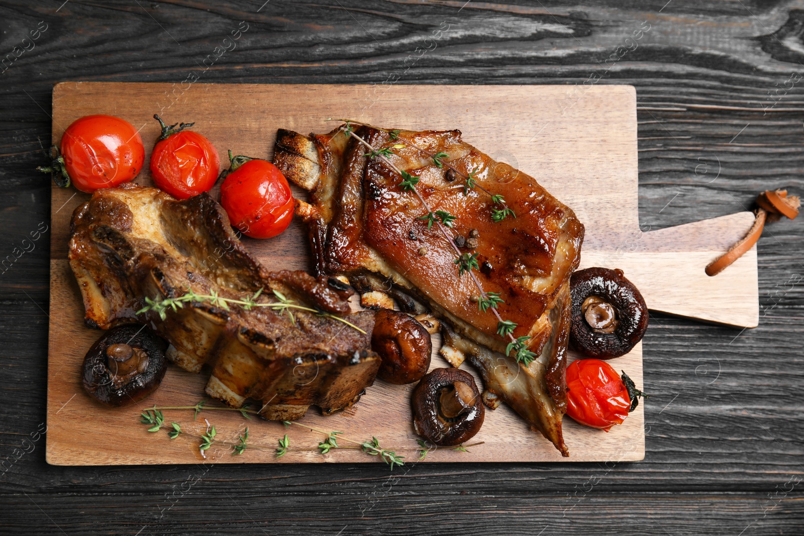Photo of Delicious roasted ribs served on black wooden table, top view