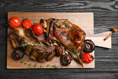 Delicious roasted ribs served on black wooden table, top view