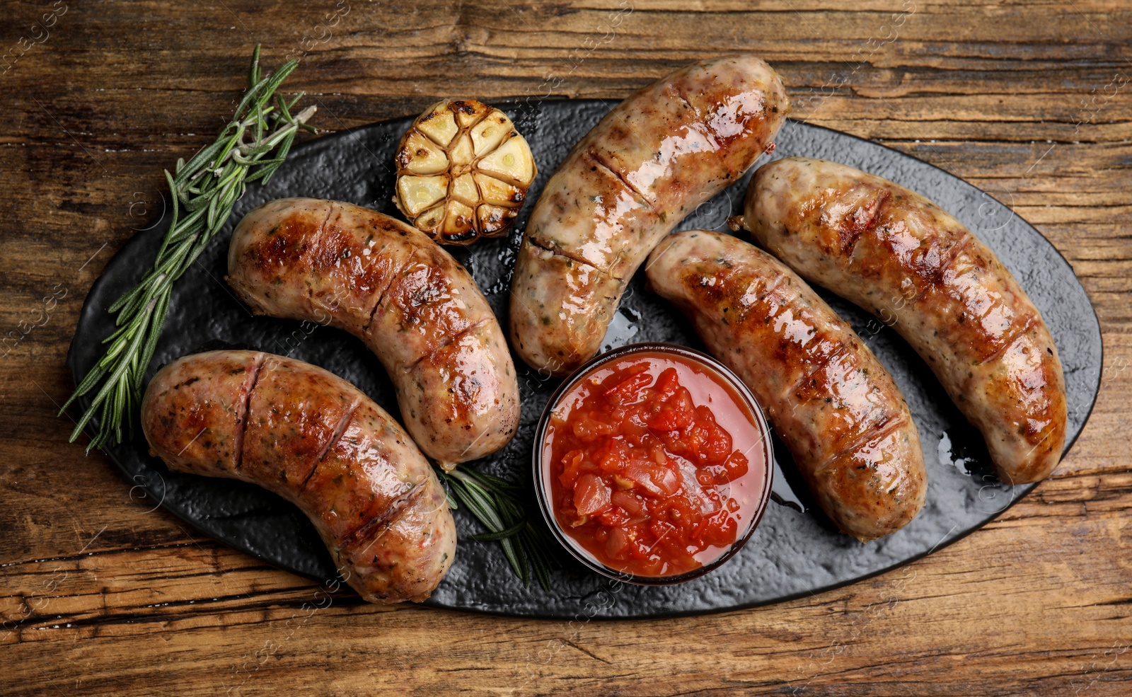 Photo of Tasty grilled sausages served on wooden table, flat lay