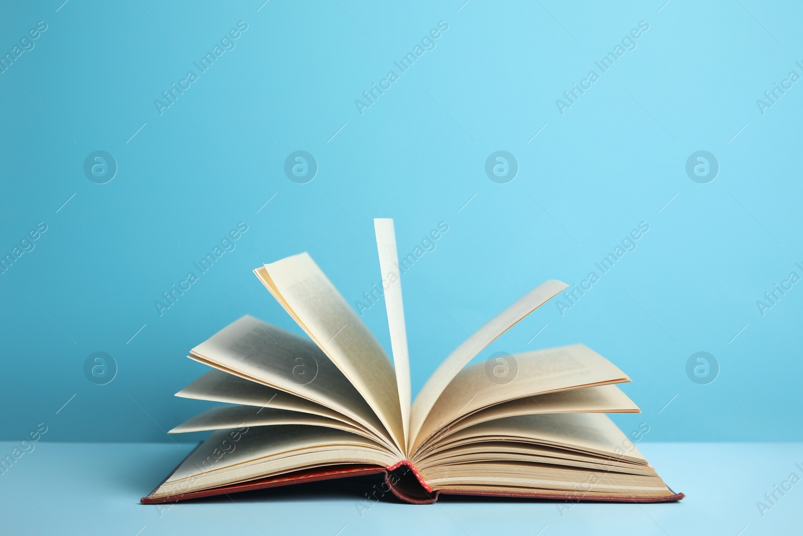 Photo of Open old hardcover book on light blue background