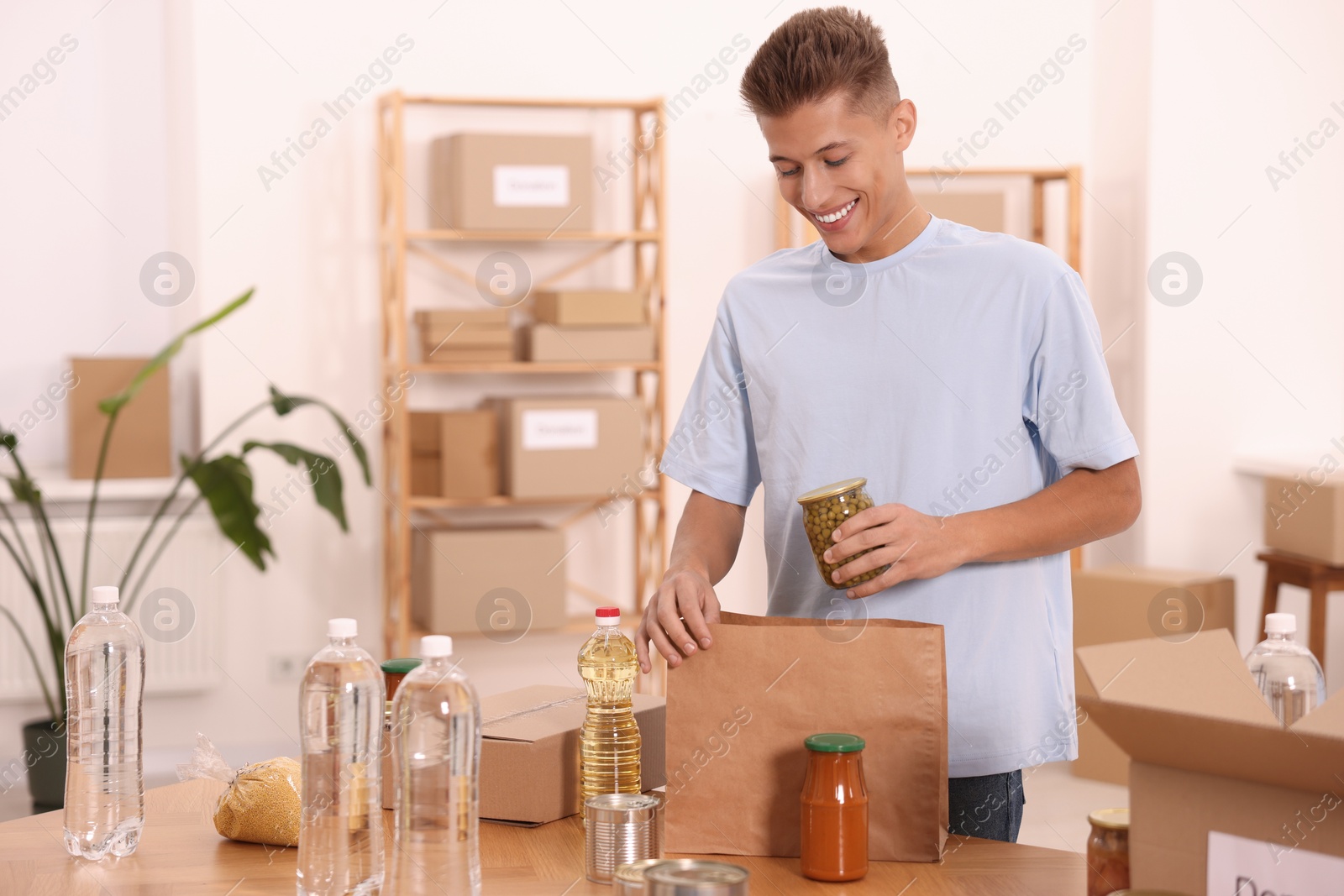 Photo of Volunteer packing food products at table in warehouse