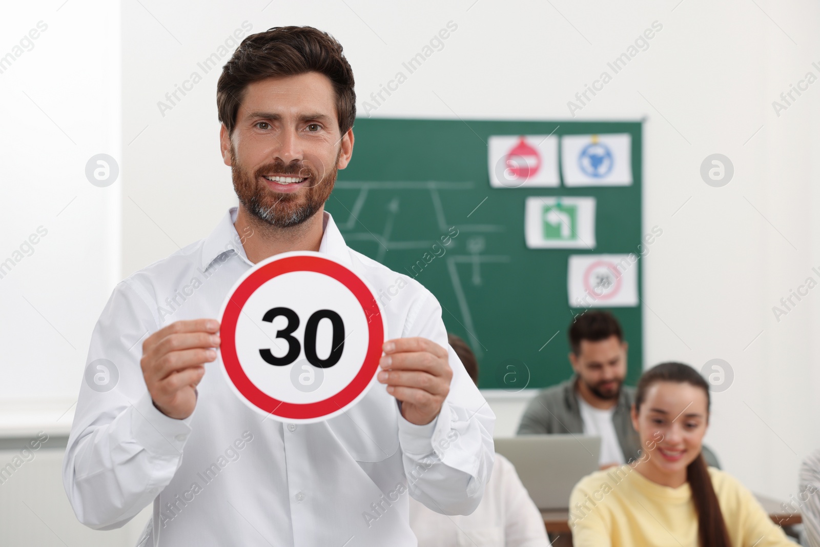 Photo of Teacher showing Speed Limit road sign during lesson in driving school. Space for text