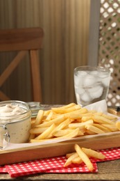 Photo of Delicious french fries served with sauce on wooden table, closeup