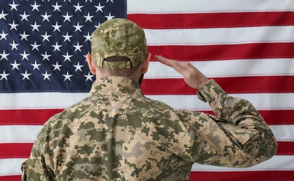 Photo of Soldier in uniform against United states of America flag, back view