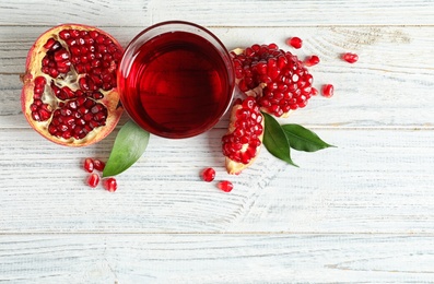 Photo of Glass of pomegranate juice and fresh fruits on wooden background, top view with space for text