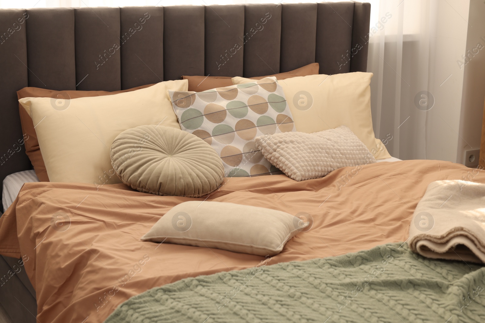 Photo of Large comfortable bed with soft pillows and blanket in room. Home textile