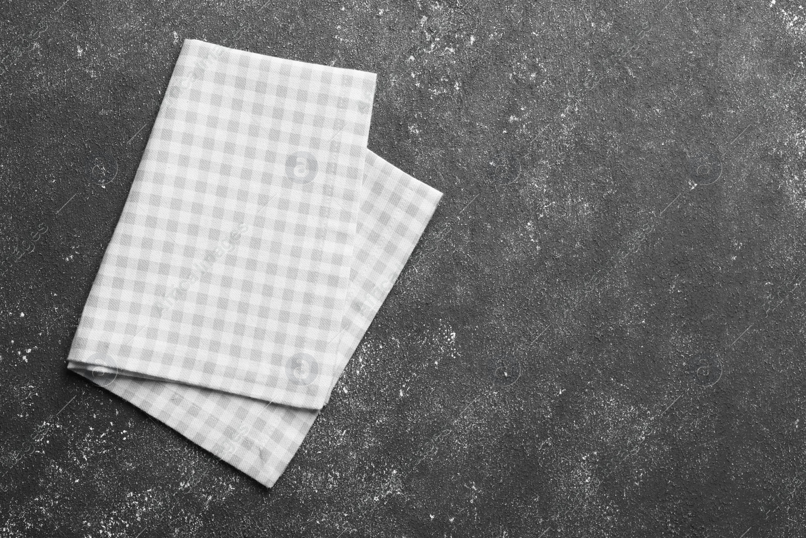 Photo of Beige checkered tablecloth on black textured table, top view. Space for text