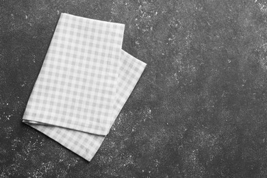 Photo of Beige checkered tablecloth on black textured table, top view. Space for text