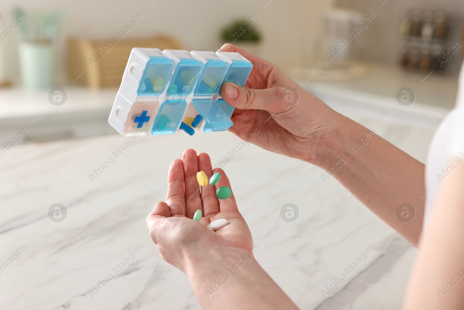 Photo of Woman with pills and organizer at white marble table, closeup