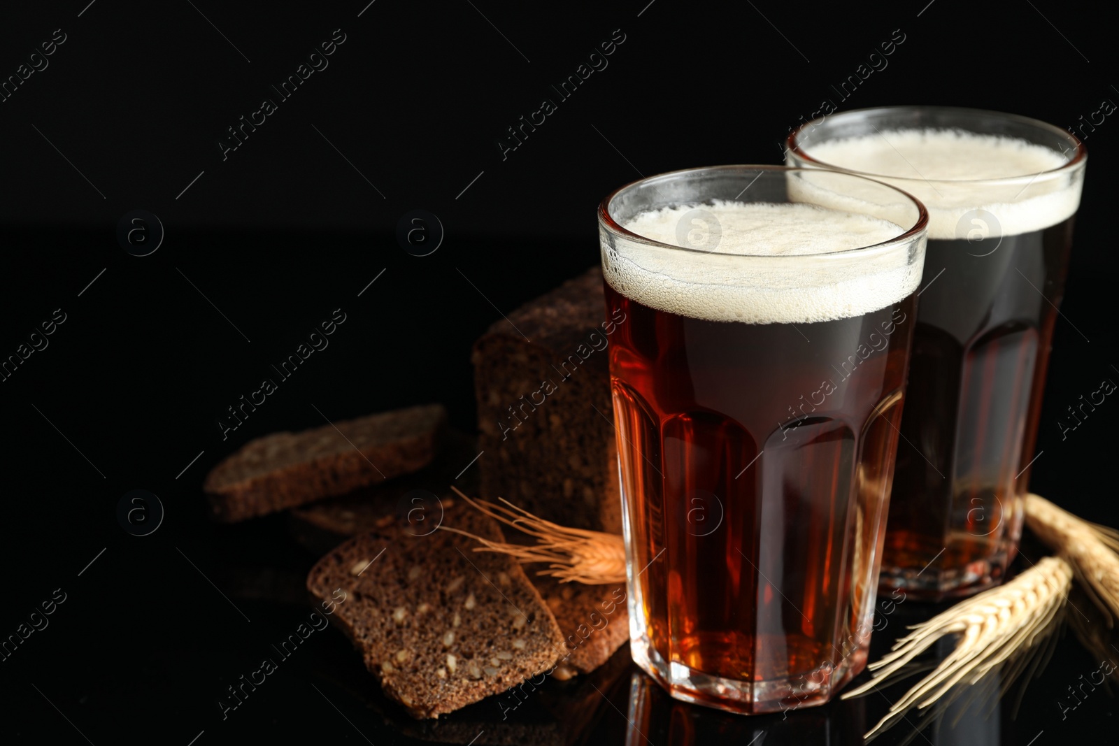 Photo of Delicious kvass, bread and spikes on black background