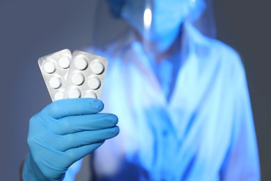 Photo of Scientist in protective gloves holding pills, focus on hand. Space for text