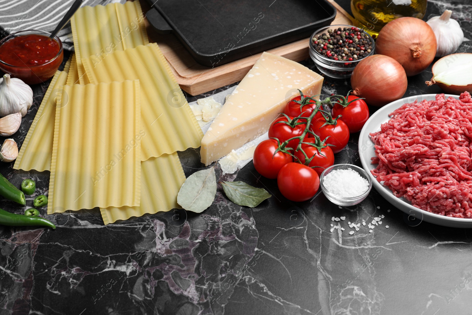 Photo of Fresh ingredients for lasagna on black marble table
