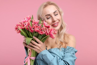 Photo of Happy young woman with beautiful bouquet on dusty pink background