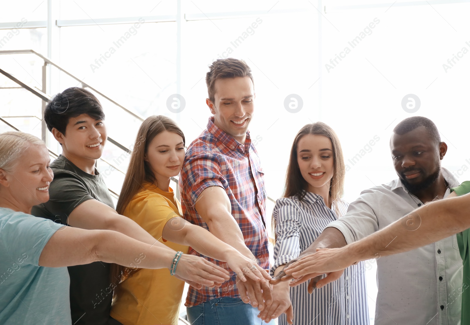 Photo of People putting hands together indoors. Unity concept