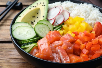 Delicious poke bowl with salmon and vegetables on wooden table, closeup