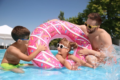 Photo of Father and children having fun in swimming pool. Family vacation