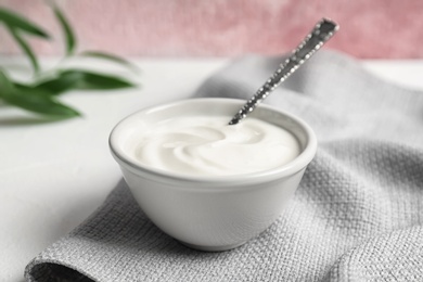 Photo of Bowl and spoon with yummy yogurt on table