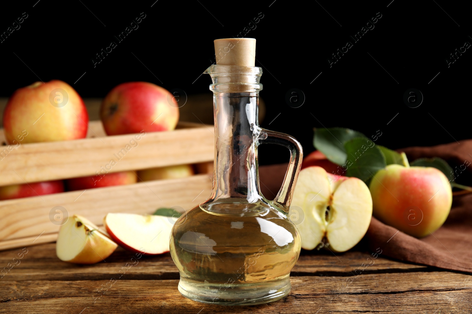 Photo of Natural apple vinegar and fresh fruits on wooden table