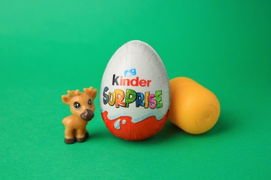 Photo of Slynchev Bryag, Bulgaria - May 25, 2023: Kinder Surprise Egg, plastic capsule and toy deer on green background