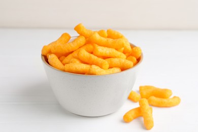 Photo of Bowl with crunchy cheesy corn snack on white table, closeup