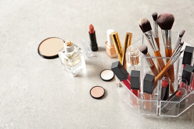 Lipstick holder with different makeup products on grey background. Space for text