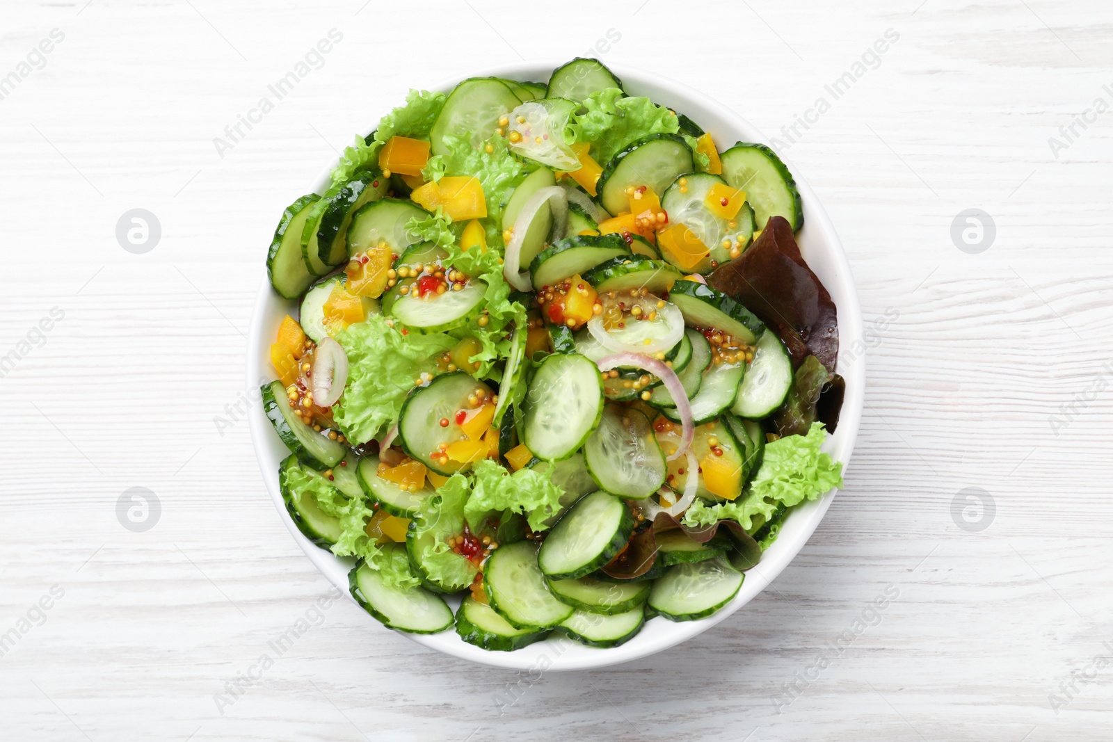 Photo of Bowl of delicious cucumber salad on white wooden table, top view