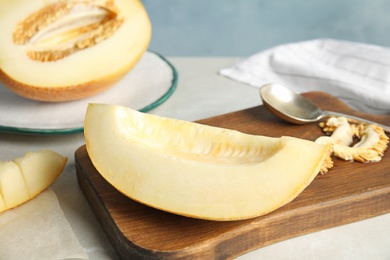 Wooden board with tasty cut ripe melon on table