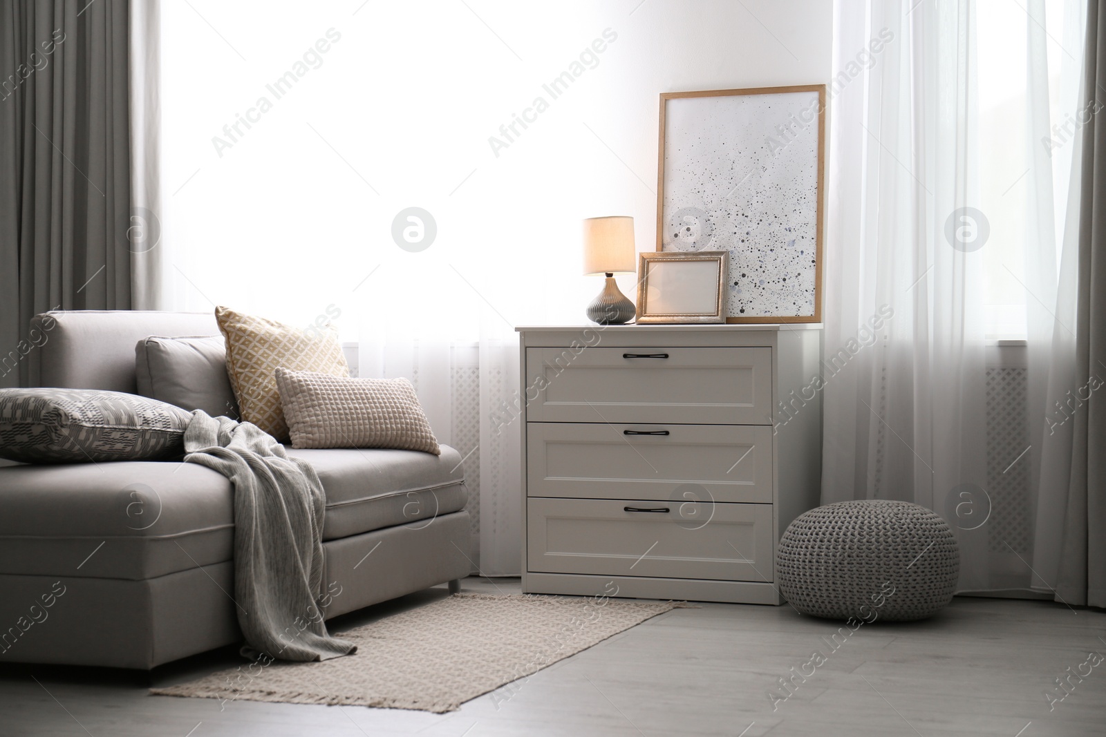 Photo of Modern stylish chest of drawers near window in living room. Interior design