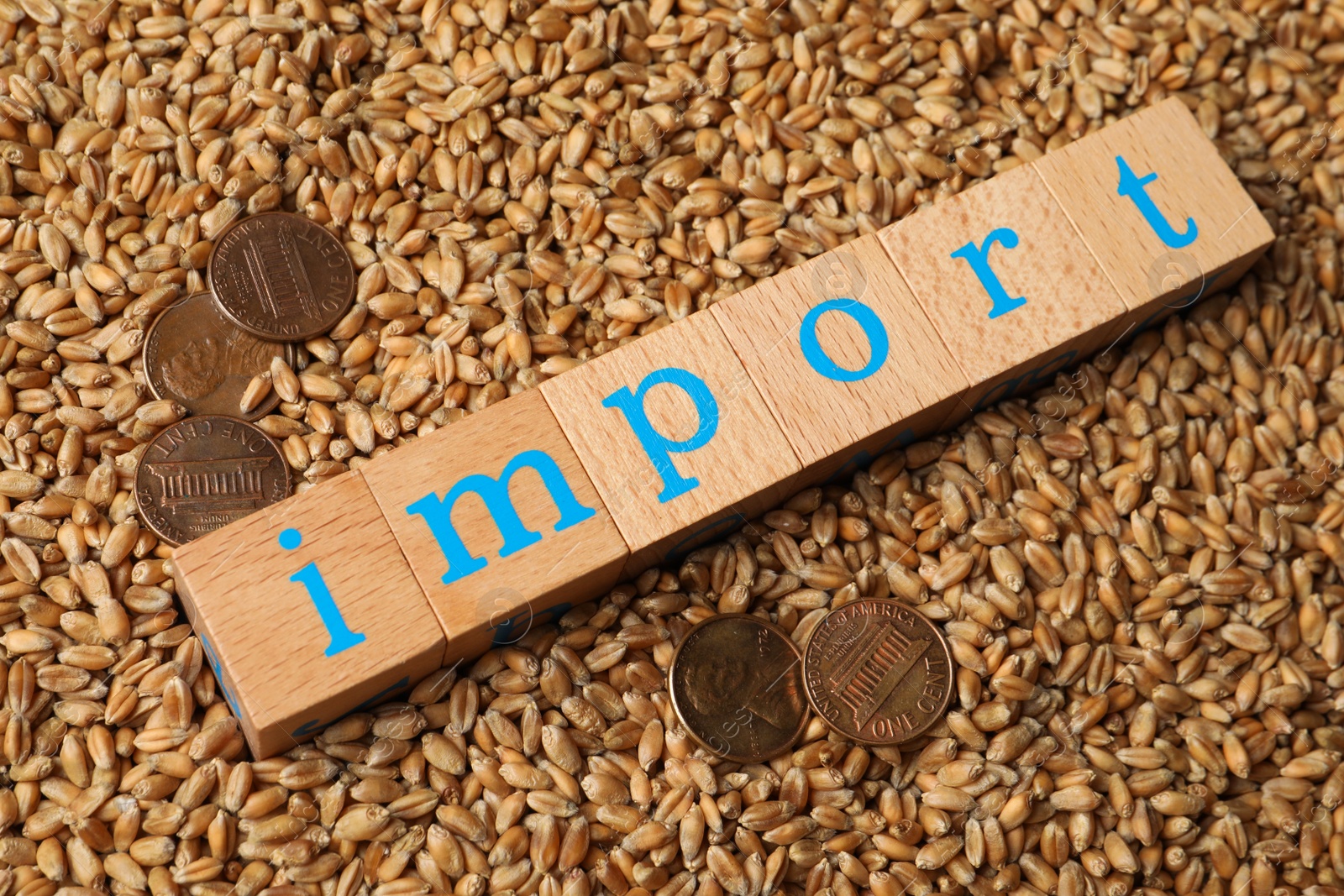 Photo of Word Import made of wooden cubes and coins on wheat grains, above view