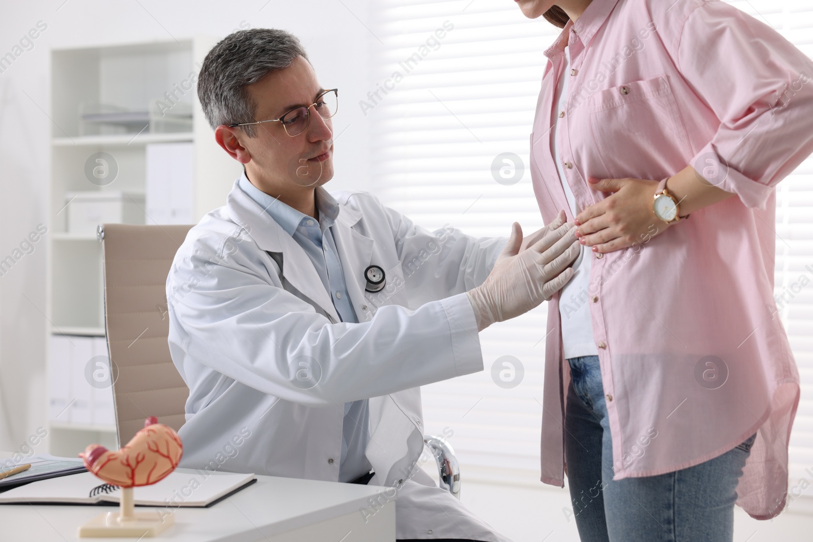 Photo of Gastroenterologist examining patient with stomach pain in clinic