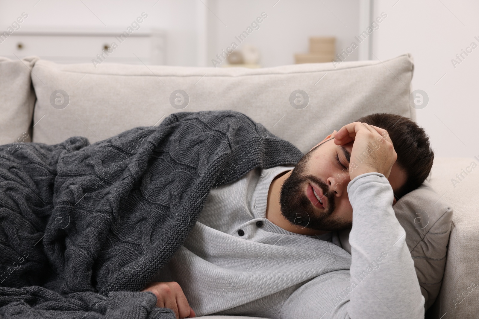 Photo of Man suffering from headache on sofa at home