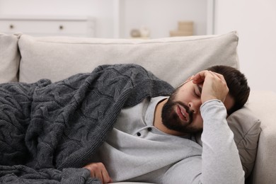 Man suffering from headache on sofa at home