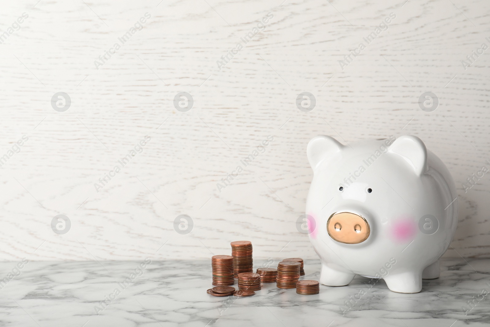 Photo of Piggy bank and different height coin stacks on table. Space for text