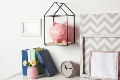 Photo of Cute piggy bank on shelf indoors. Stylish interior element