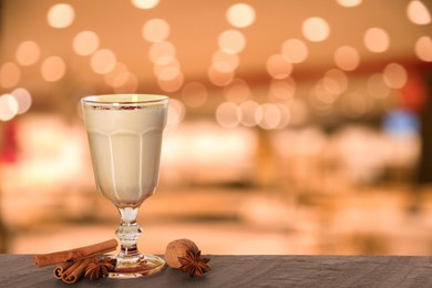 Glass of delicious eggnog on table in bar, space for text