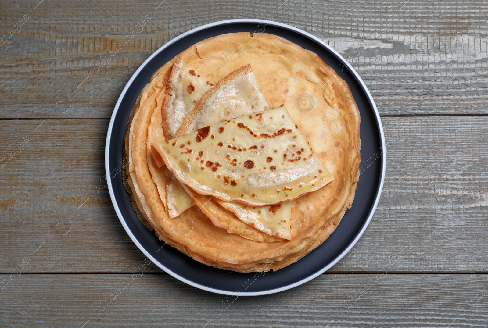 Photo of Stack of delicious crepes on grey wooden table, top view