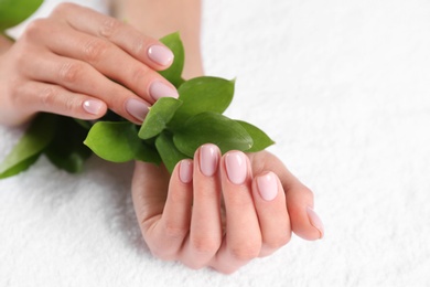 Photo of Closeup view of beautiful female hands with green leaves on towel, space for text. Spa treatment