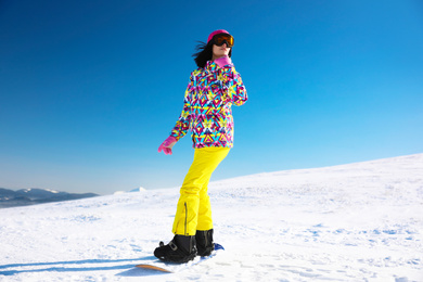 Photo of Young woman snowboarding on hill. Winter vacation