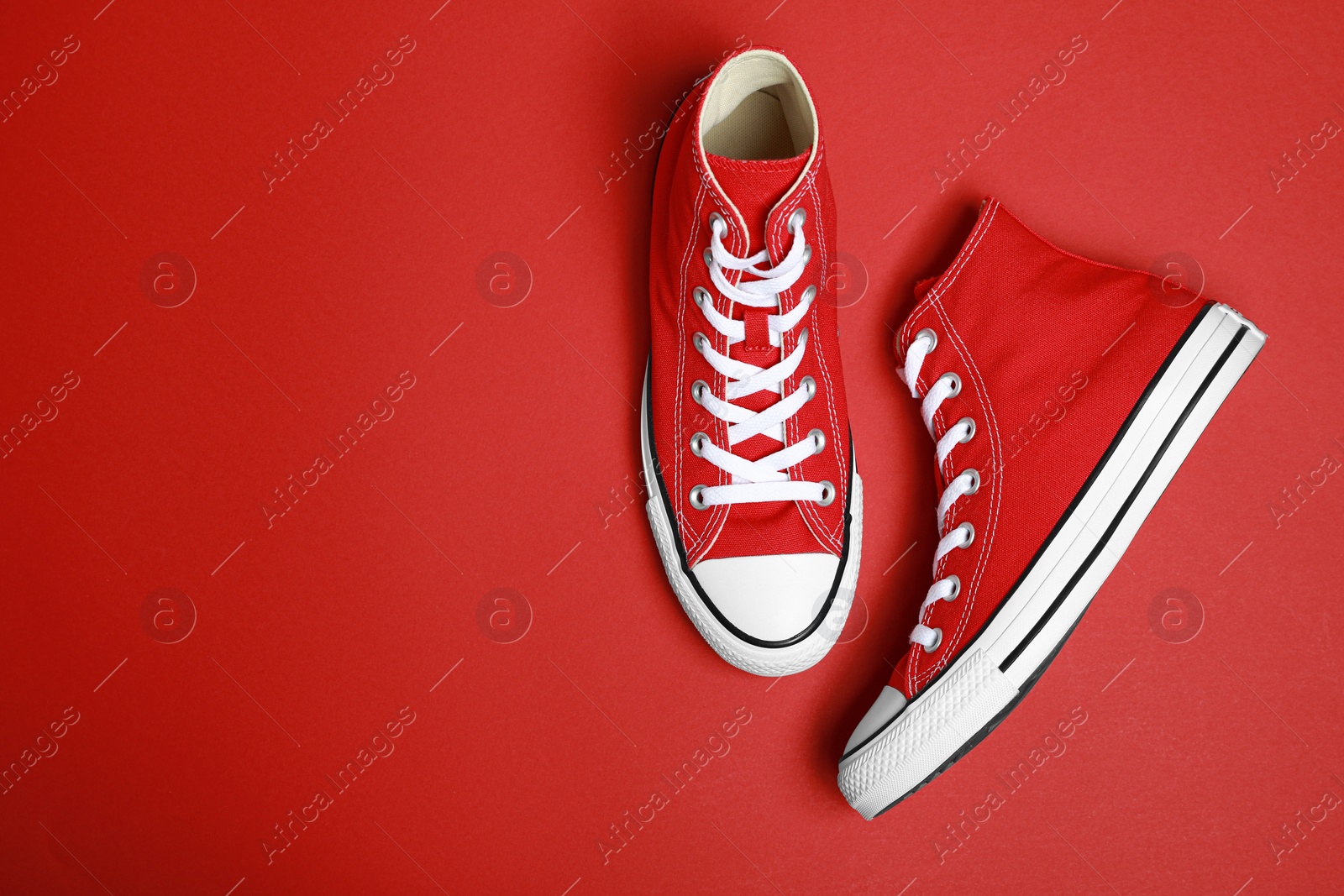 Photo of Pair of new stylish sneakers on red background, flat lay. Space for text