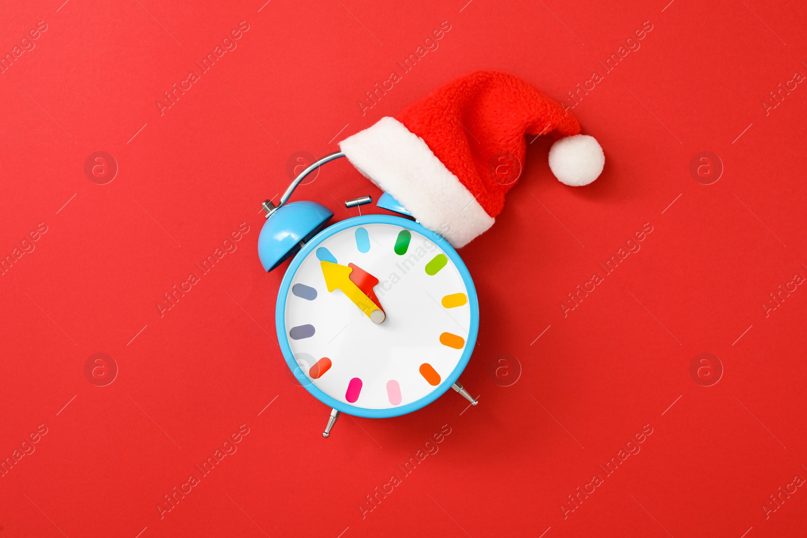 Photo of Alarm clock with Santa hat on red background, top view. New Year countdown