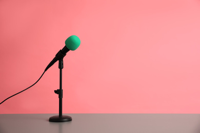 Photo of Microphone on table against pink background, space for text. Journalist's work