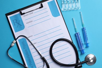 Photo of Clipboard with medical prescription form, stethoscope, ampoules and syringes on light blue background, flat lay
