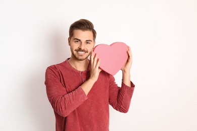 Portrait of young man with decorative heart on white background